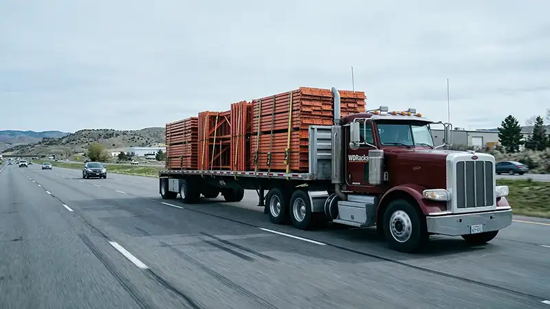 Flatbed truck transporting racking on highway.