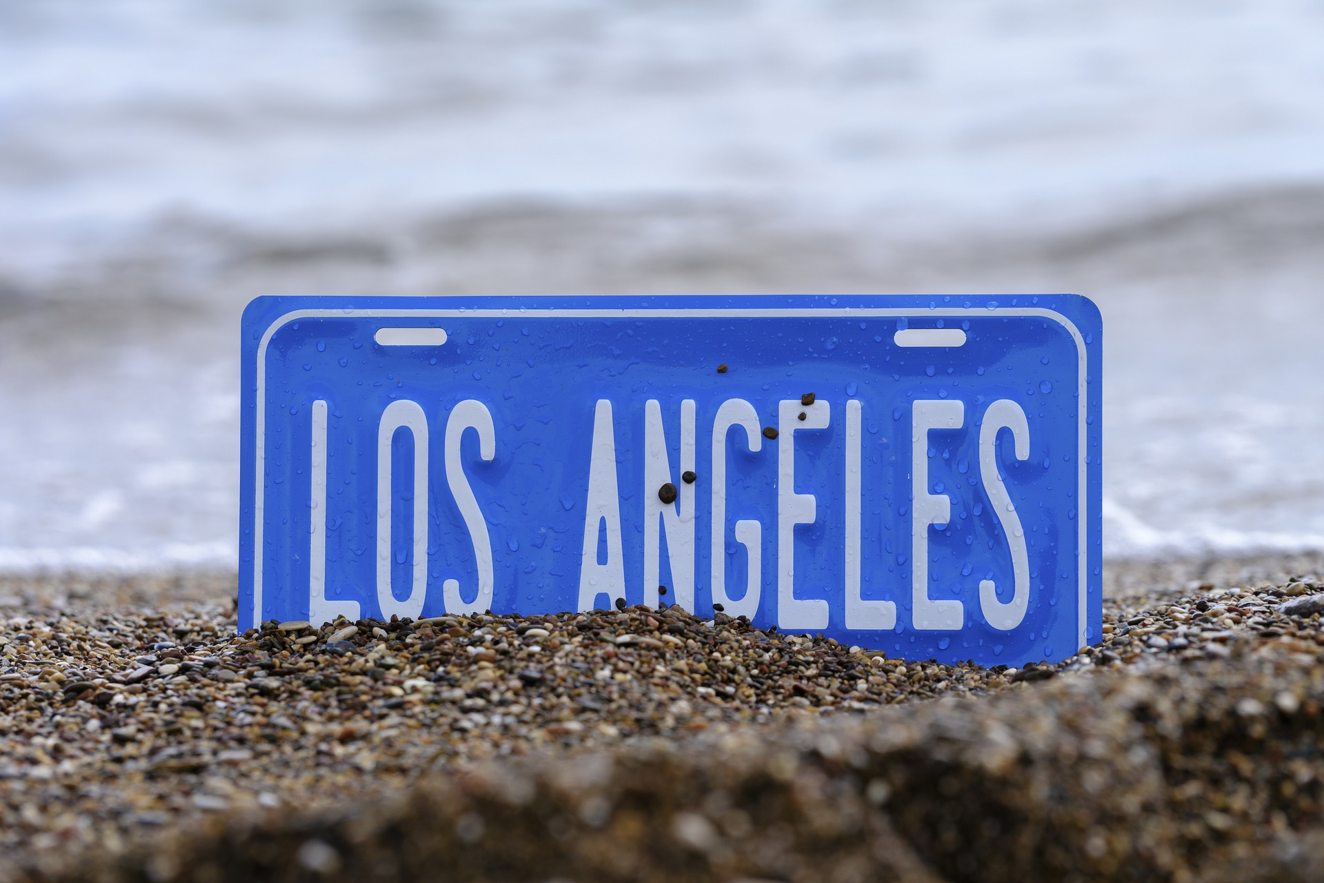 los angeles license plate slightly buried in sand